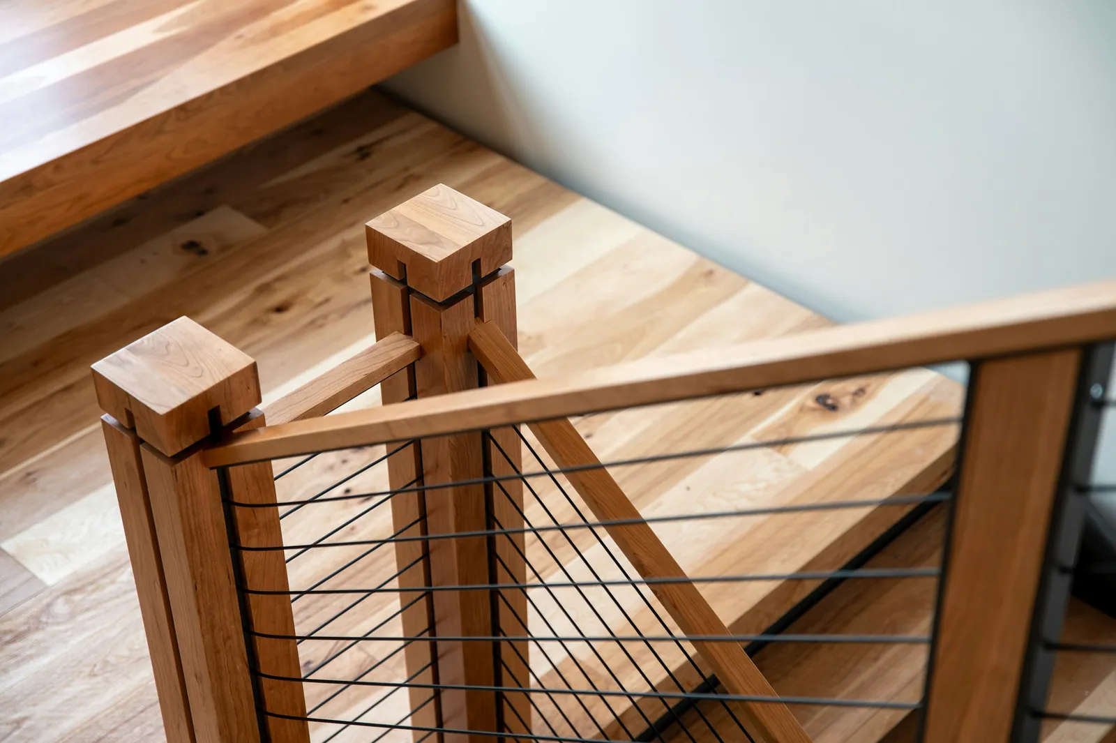 Cherry wood stair rail with black steel cables, seen from above