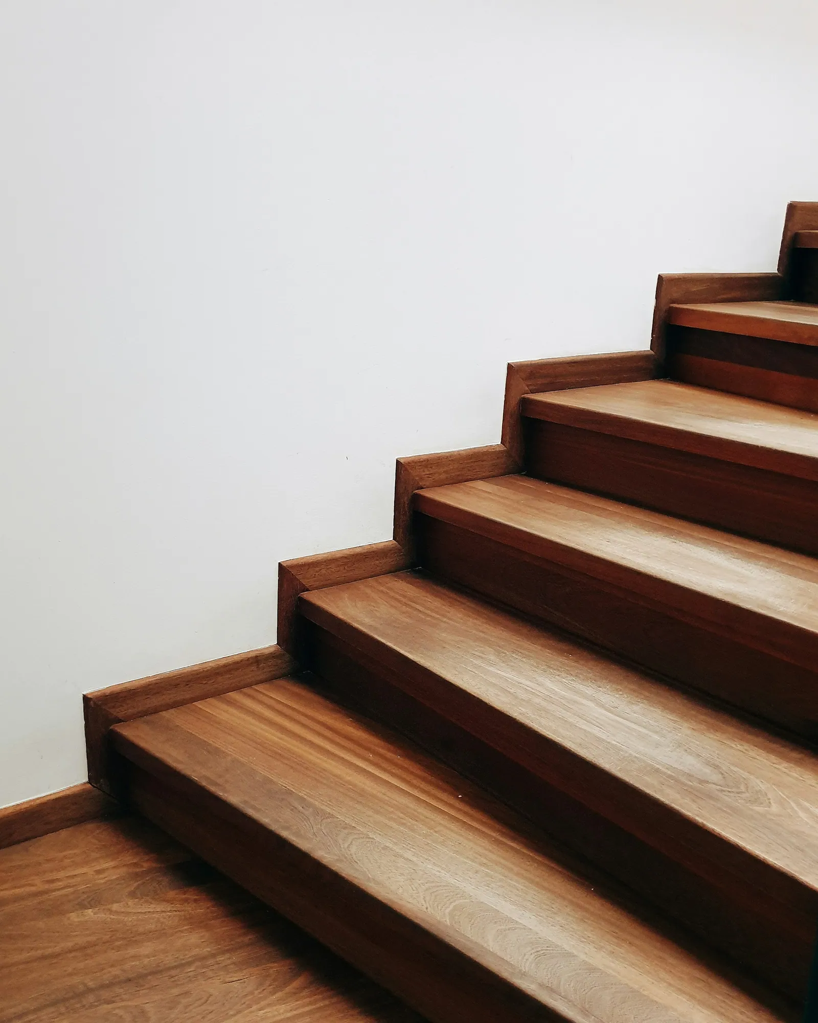 Close view of hardwood stair treads stepping up beside a white wall
