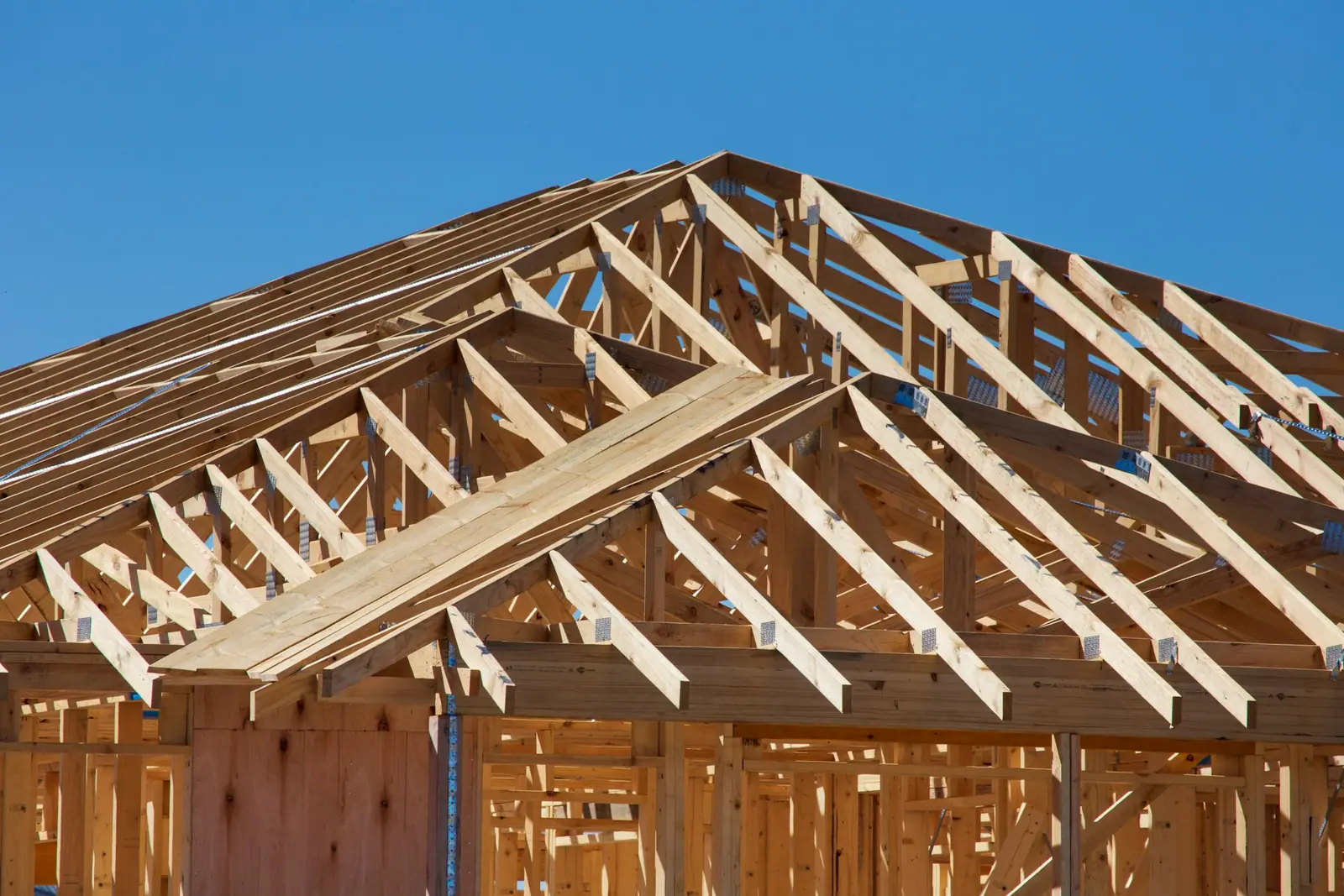 New roof trusses over timber-framed walls against a blue sky