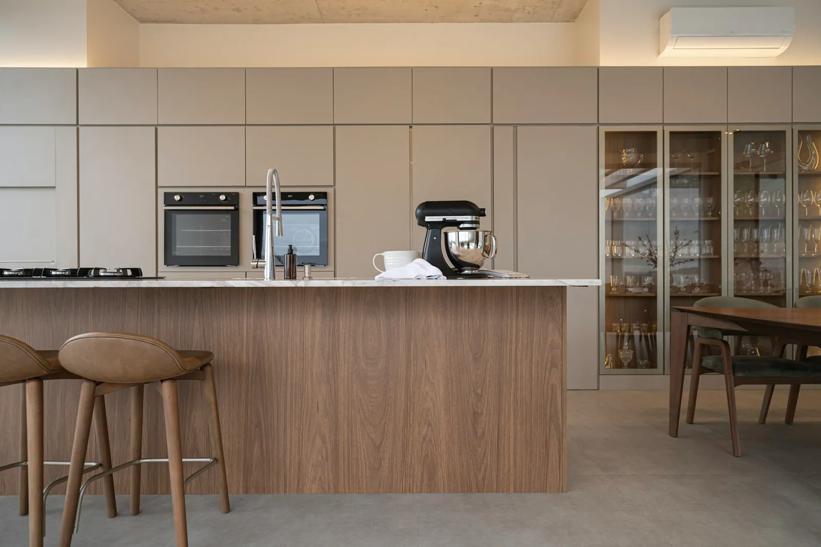 Kitchen with a walnut island, pale stone counters and tall built-in cabinets
